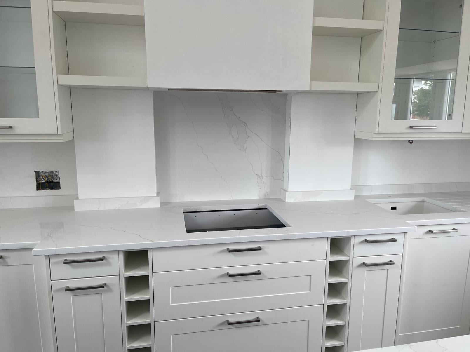 White Shaker kitchen with induction hob, marble-effect worktop and splashback and built-in wine rack
